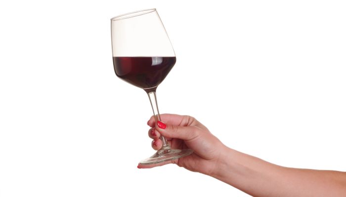 Pessoa demonstrando como segurar taça de vinho pela haste da taça
