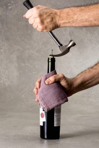 Simulação de como abrir uma garrafa de vinho utilizando um parafuso e martelo