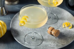 Coquetel french 75 servido na taça com enfeite de limão.