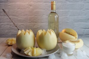 Coquetel Melvin servido em melões, e garrafa de vinho branco.